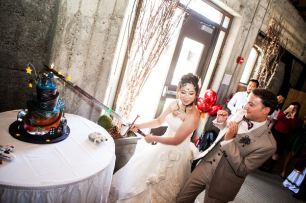 cutting wedding cake - A costume wedding with winged shoes, fist bumps, and an Indiana Jones groom cutting wedding cake