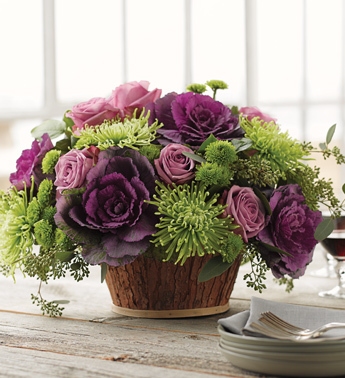 Lavender roses, green spider mums, ‘Kermit’ pom-pom mums, and purple kale, all arranged in a rustic bark basket. (From 1800flowers.com, no less!)