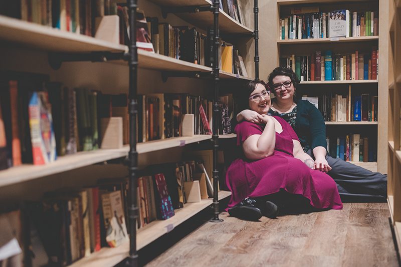Love in the stacks: a literary engagement shoot with two cute brides-to-be