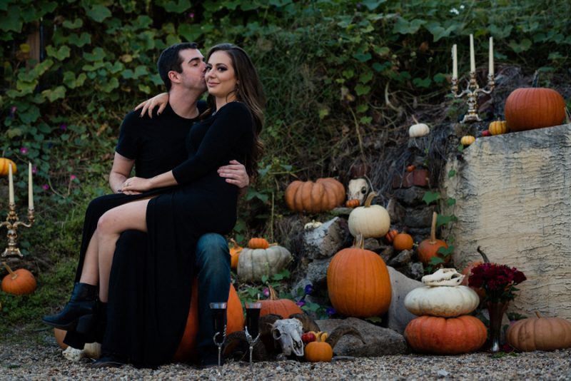 A cemetery engagement photo shoot with pumpkins, colorful smoke, and their Best Cats