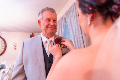 Bride attaching her father's wood marigold boutonniere with a magnet backing.