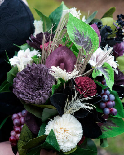 Bouquet of wood flowers dyed in various shades of purple and burgundy, with ivory and black flowers, too.