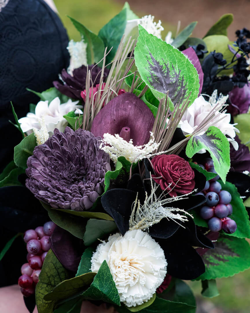 Bouquet of wood flowers dyed in various shades of purple and burgundy, with ivory and black flowers, too.