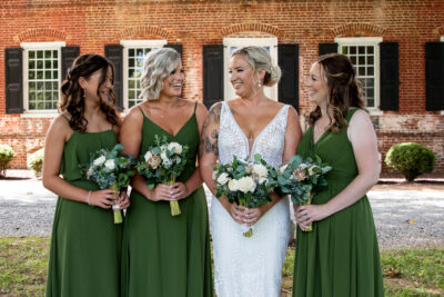 Bride with 3 bridesmaids in green dresses, all holding bouquets of ivory wood flowers and eucalyptus.