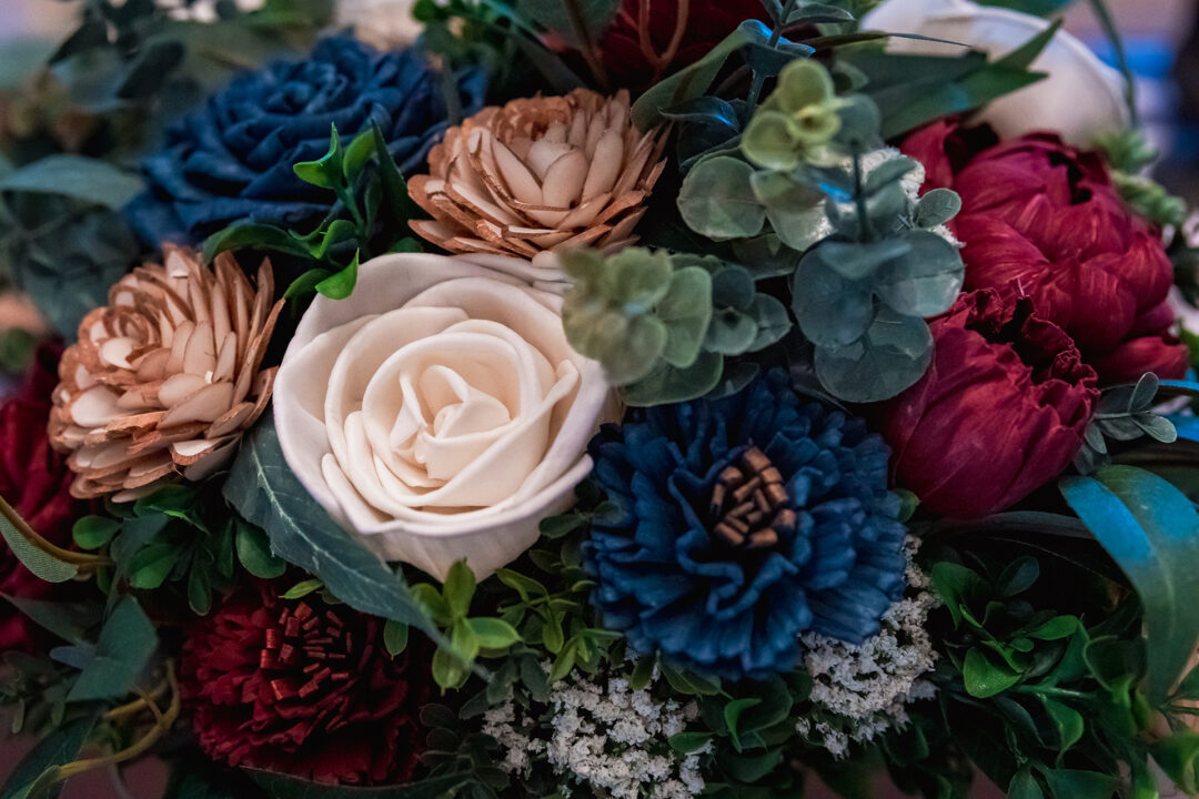 Close up of an ivory, burgundy, and navy bouquet of wood flowers.