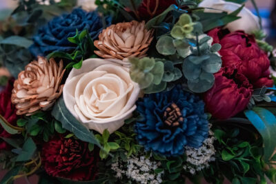 Close up of an ivory, burgundy, and navy bouquet of wood flowers.