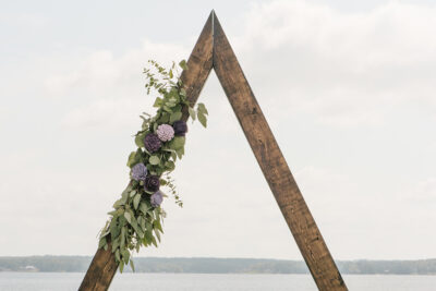 Triangle wood arch with eucalyptus and wood flower swag on the left side.