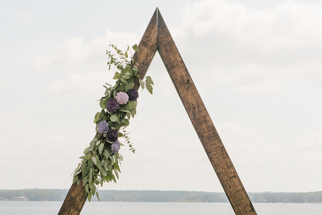 Triangle wood arch with eucalyptus and wood flower swag on the left side.