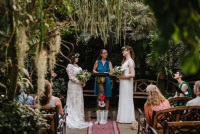 A butterfly conservatory makes for a stunning backdrop for this elopement. A natural frame of tropical plants surrounds the couple and their guests.