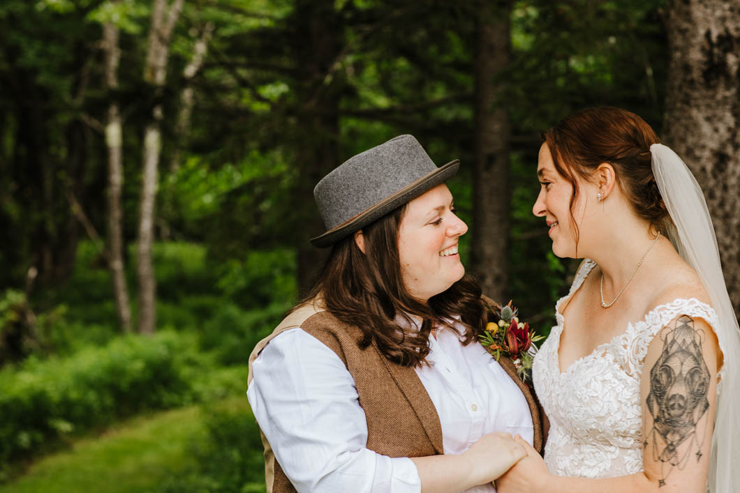 two people who just got married, are wearing their wedding day attire while look lovingly into each other's eyes