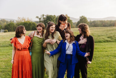 A group of brightly dressed wedding guests enjoy social hour and pose for a photo