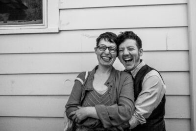 LGBTQIA+ couple laugh and embrace at a DIY wedding on Long Island NY.