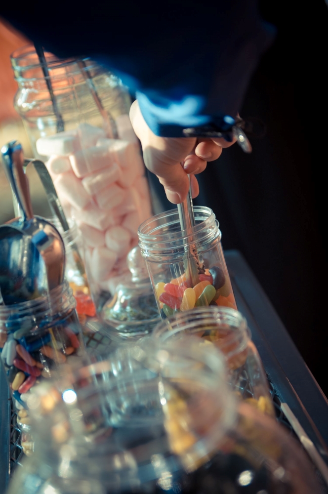 Hands reaching with tongs for candies