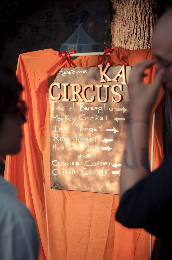 A wooden panel with gold lettering reporting the activities and the name of the spouses, with an orange drape on it.
