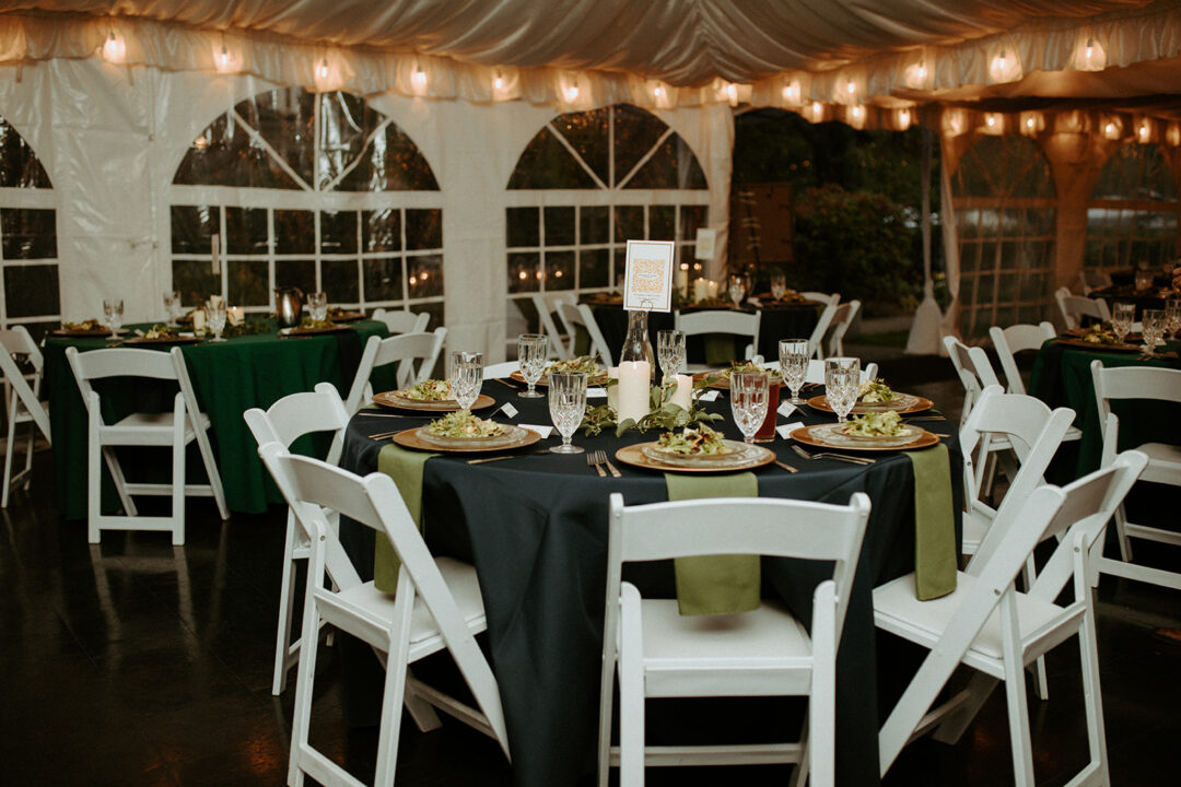 Dining tables set at a wedding reception at the Victorian Belle Mansion in Portland, Oregon. The tables have blue tablecloths and green napkins. Photo by Hannah Alena