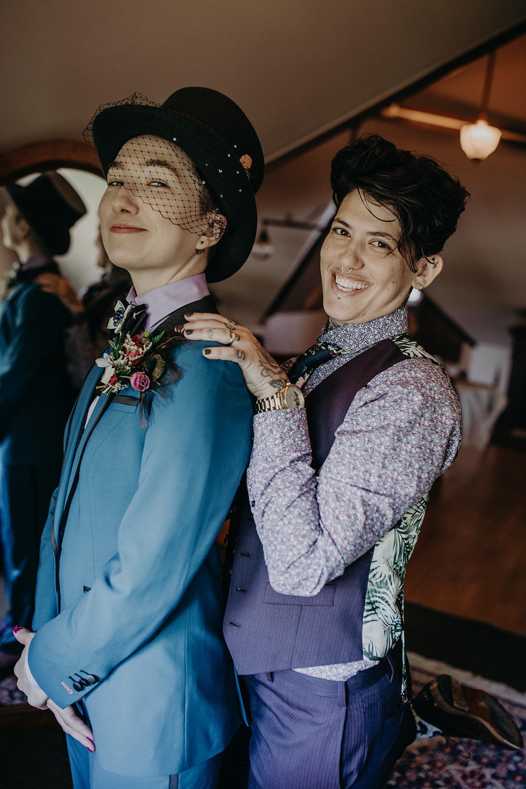 Two people in suits stand together smiling